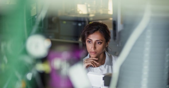 A woman seated at a desk looks at data