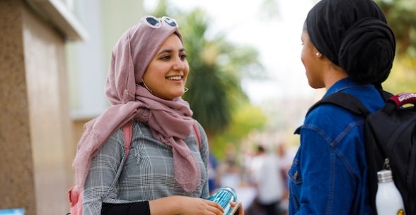 ASU undergraduate students chat outside on their way from class