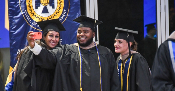 Image of Thunderbird graduates taking a selfie together at the Fall 2021 convocation ceremony